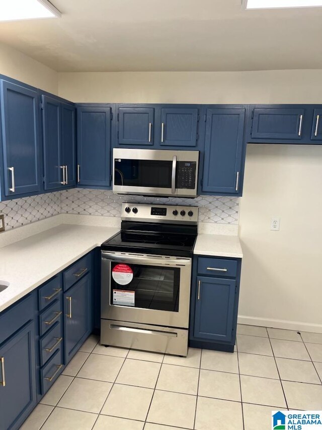 kitchen with blue cabinets, appliances with stainless steel finishes, light tile patterned floors, and tasteful backsplash