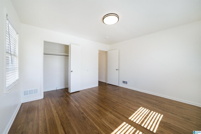 unfurnished bedroom with a closet and dark wood-type flooring