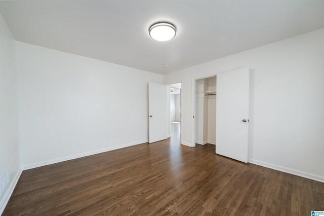 unfurnished bedroom with dark wood-type flooring and a closet