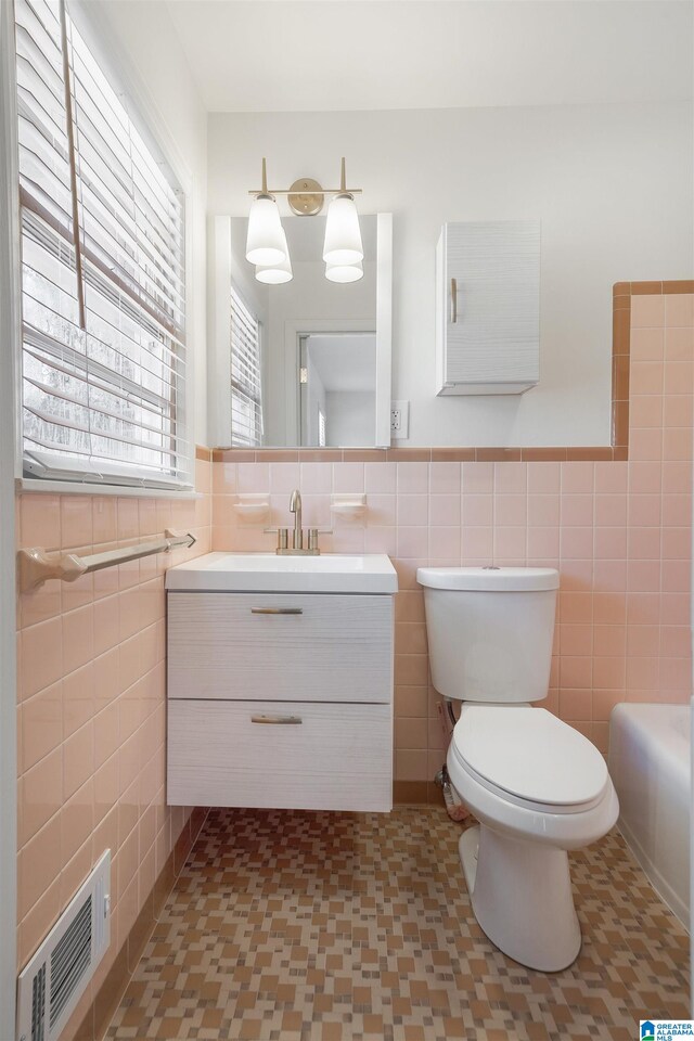 bathroom featuring vanity, tile walls, a bathing tub, and toilet