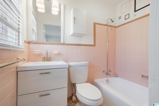 full bathroom with tile walls, vanity, toilet, and tiled shower / bath