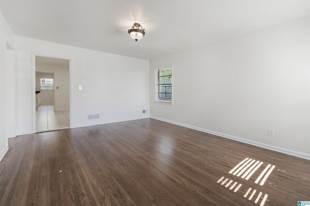 empty room with dark hardwood / wood-style flooring and a healthy amount of sunlight