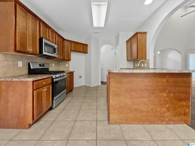 kitchen featuring stainless steel appliances, backsplash, light tile patterned floors, and kitchen peninsula