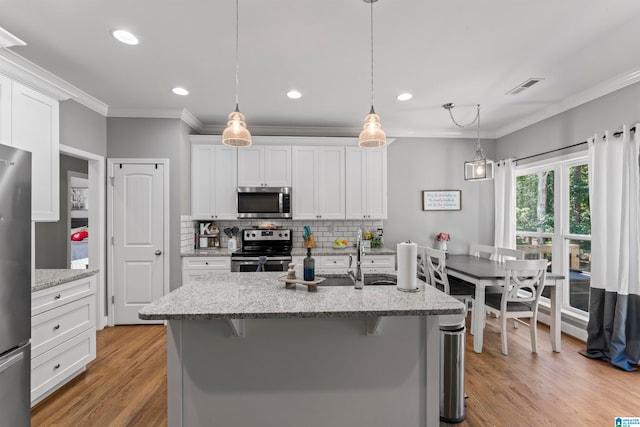 kitchen with light wood-type flooring, white cabinetry, stainless steel appliances, a breakfast bar area, and light stone countertops