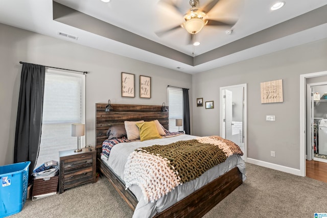 bedroom featuring a spacious closet, carpet floors, a tray ceiling, ceiling fan, and ensuite bathroom