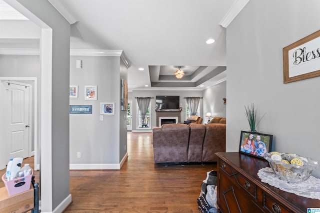 living room featuring dark hardwood / wood-style flooring, a tray ceiling, and crown molding