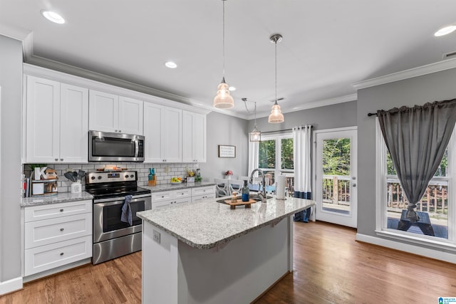 kitchen featuring sink, an island with sink, white cabinets, stainless steel appliances, and hardwood / wood-style floors