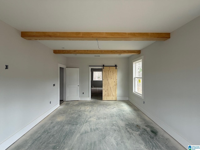 spare room featuring beamed ceiling, baseboards, and a barn door