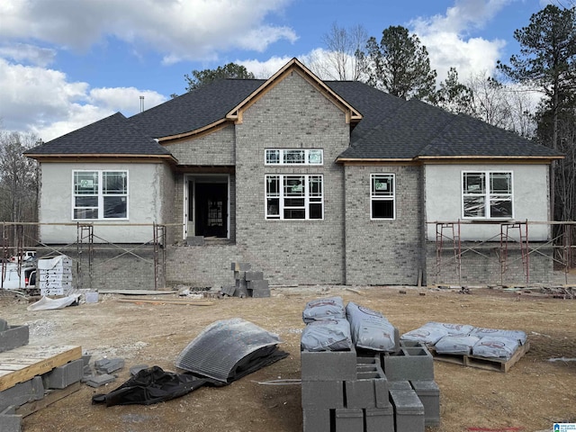 view of front of property featuring brick siding and roof with shingles