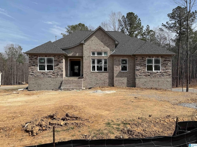 view of front of home featuring brick siding and roof with shingles