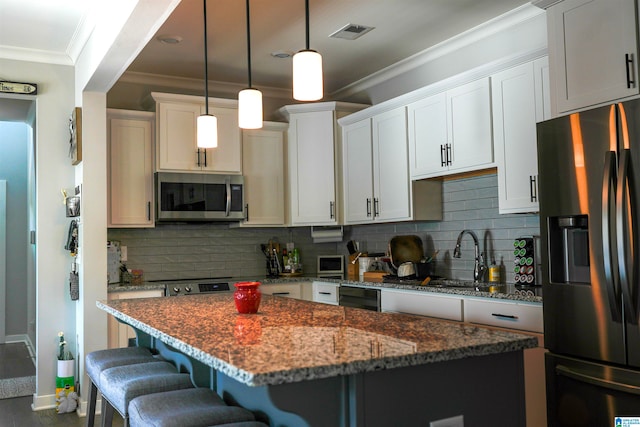 kitchen with tasteful backsplash, a kitchen island, appliances with stainless steel finishes, dark stone countertops, and decorative light fixtures