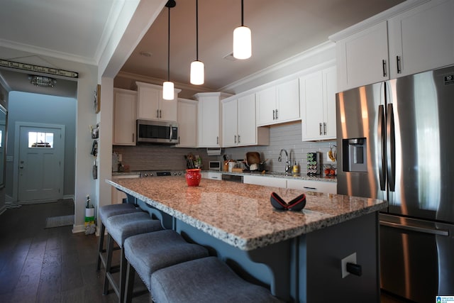 kitchen featuring white cabinets, light stone countertops, stainless steel appliances, and a kitchen island