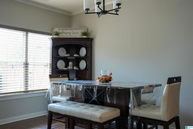 dining area with dark wood-type flooring, crown molding, and an inviting chandelier