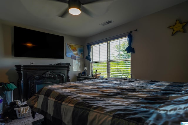 carpeted bedroom featuring a fireplace and ceiling fan