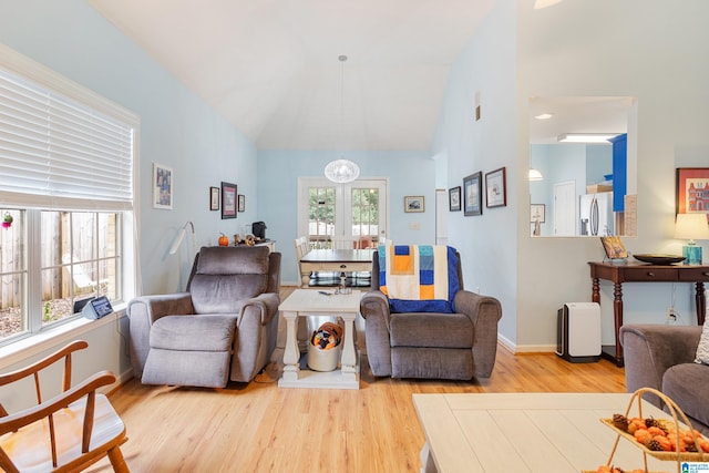 living room featuring french doors, light wood-type flooring, vaulted ceiling, and plenty of natural light