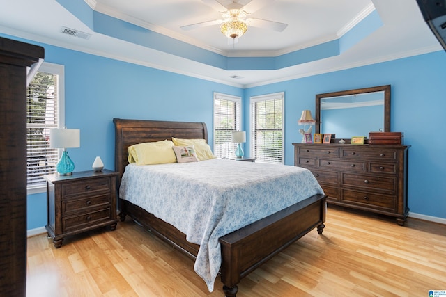 bedroom with a tray ceiling, multiple windows, ceiling fan, and light hardwood / wood-style floors