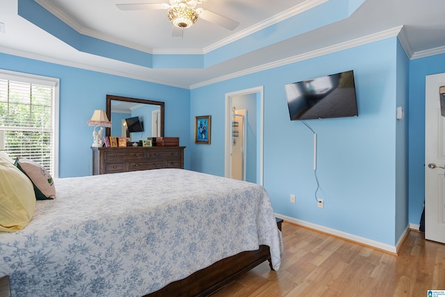 bedroom with hardwood / wood-style flooring, ceiling fan, a raised ceiling, and ornamental molding