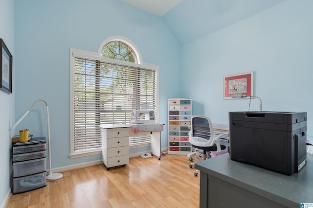 home office with light wood-type flooring and vaulted ceiling