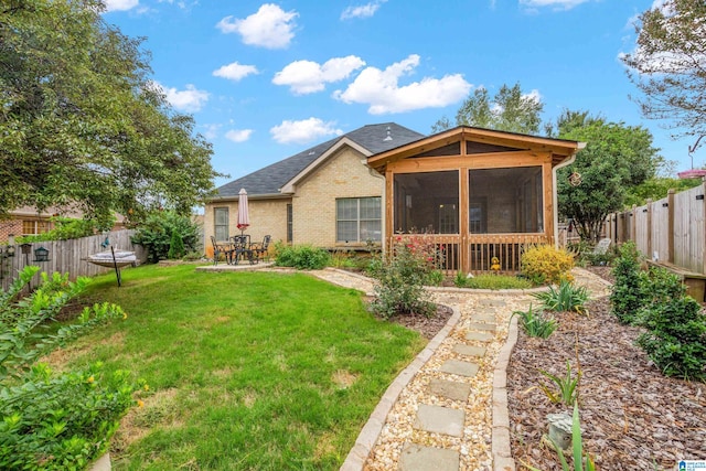 rear view of house featuring a lawn and a sunroom