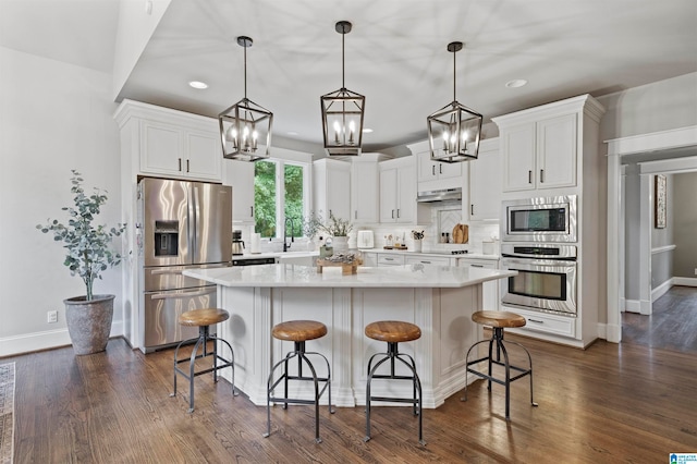 kitchen featuring appliances with stainless steel finishes, hanging light fixtures, and white cabinets