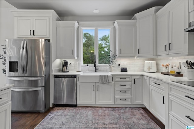 kitchen with white cabinets, appliances with stainless steel finishes, backsplash, and dark wood-type flooring