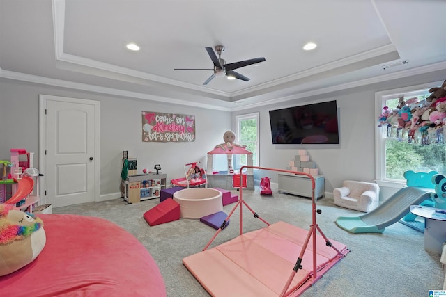 game room featuring light colored carpet, ceiling fan, a raised ceiling, and plenty of natural light