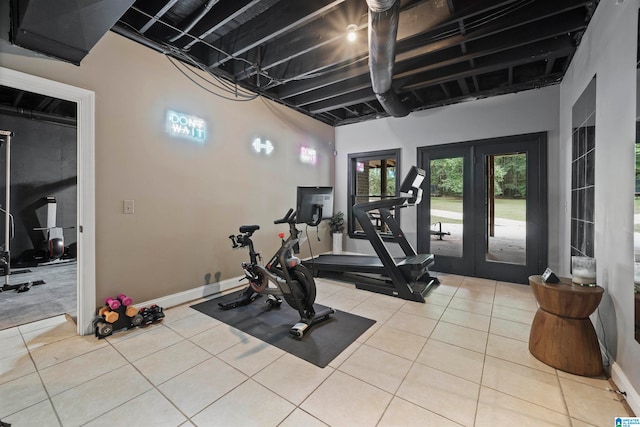 exercise room with light tile patterned floors and french doors