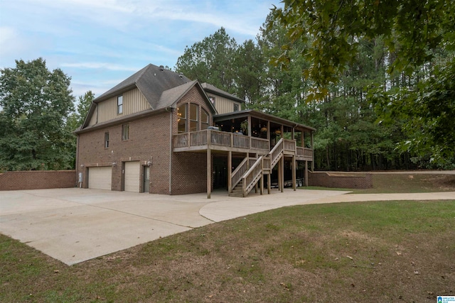 rear view of house with a wooden deck, a yard, and a garage