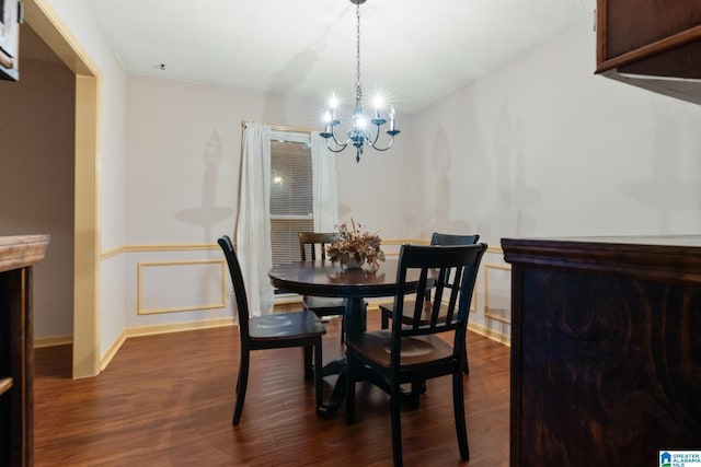 dining space with an inviting chandelier, a wainscoted wall, and dark wood-style flooring