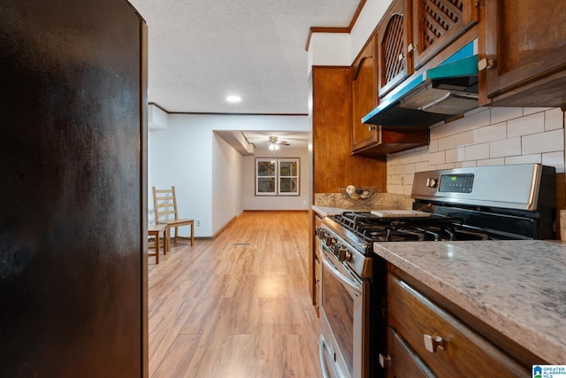 kitchen featuring light wood-type flooring, backsplash, gas stove, ceiling fan, and ornamental molding