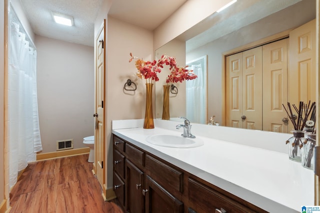 bathroom featuring vanity, hardwood / wood-style floors, a textured ceiling, and toilet