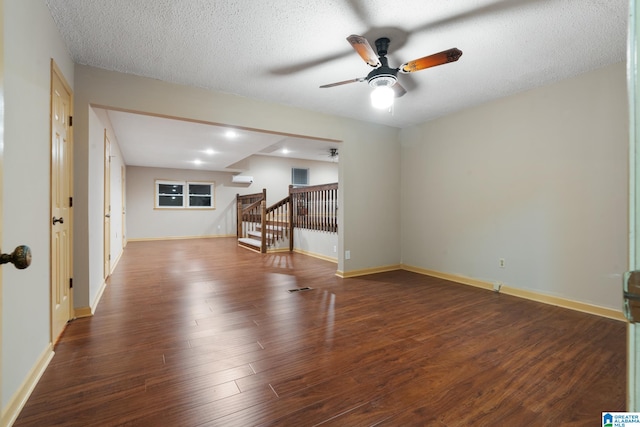 spare room featuring dark wood-type flooring, a wall mounted AC, a textured ceiling, and ceiling fan