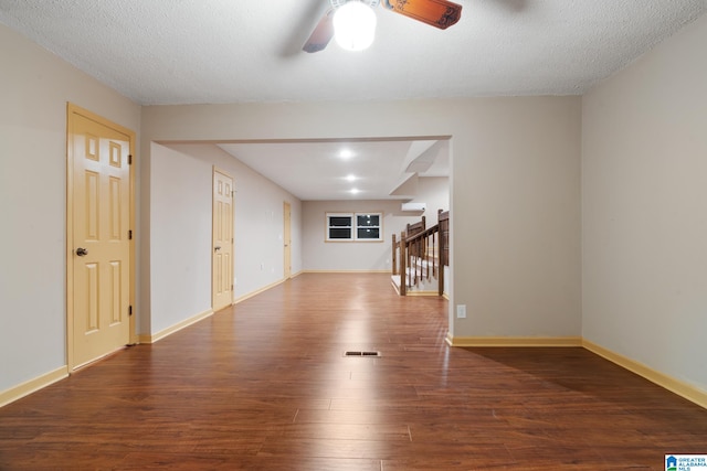 interior space featuring dark wood-type flooring, a wall unit AC, a textured ceiling, and ceiling fan