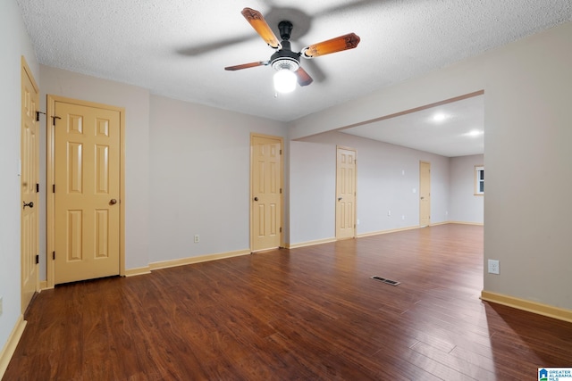 empty room with a textured ceiling, ceiling fan, and dark hardwood / wood-style flooring