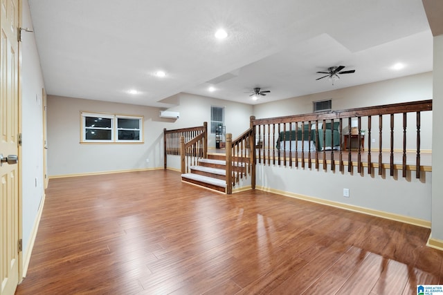 unfurnished room with hardwood / wood-style floors, a wall mounted AC, and ceiling fan