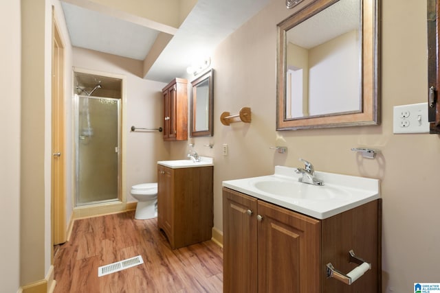 bathroom featuring vanity, toilet, a shower with shower door, and hardwood / wood-style floors