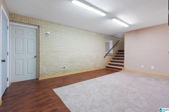 basement with dark wood-type flooring and brick wall