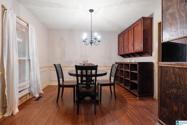 dining area with a textured ceiling, dark hardwood / wood-style flooring, and a chandelier