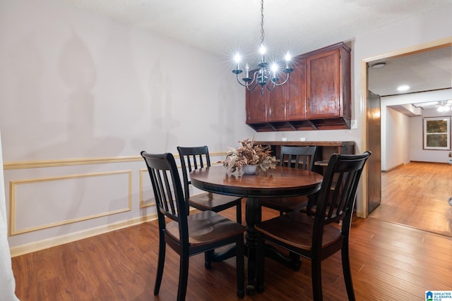 dining space featuring ceiling fan with notable chandelier, a textured ceiling, and light hardwood / wood-style floors