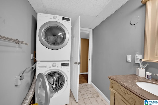 washroom with light tile patterned flooring, sink, and stacked washer and clothes dryer