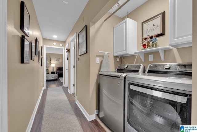 laundry room with washer and dryer, cabinets, and wood-type flooring