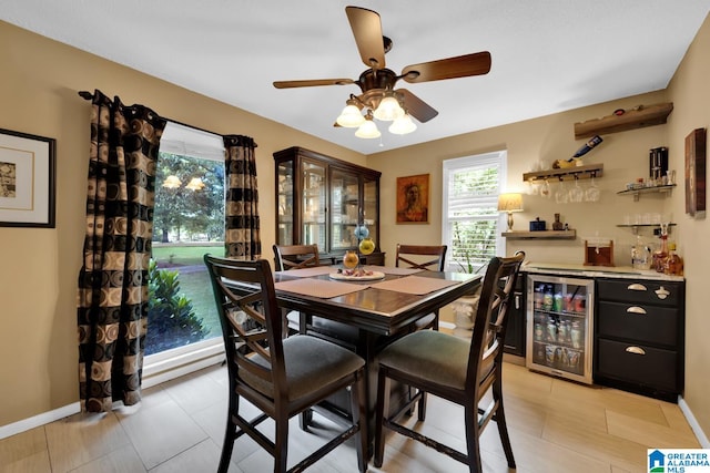 tiled dining space with ceiling fan, beverage cooler, and indoor bar