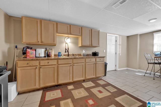 kitchen with light brown cabinetry, light tile patterned floors, and sink