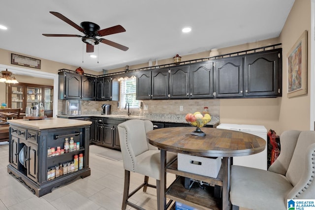 kitchen featuring ceiling fan, a center island, sink, backsplash, and light tile patterned flooring