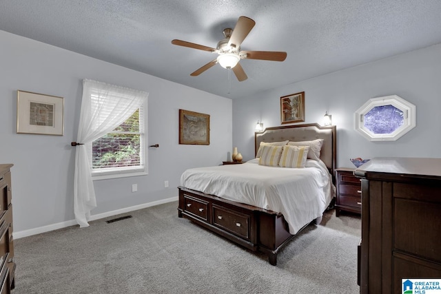 carpeted bedroom featuring ceiling fan and a textured ceiling