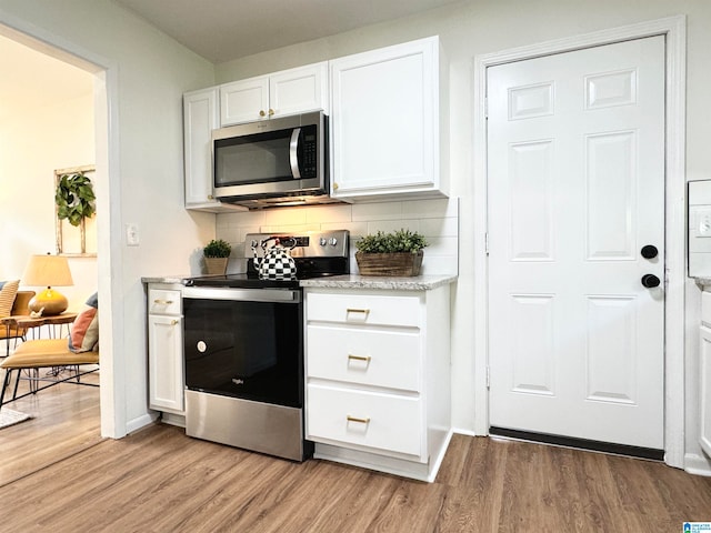 kitchen featuring light hardwood / wood-style flooring, decorative backsplash, white cabinetry, and appliances with stainless steel finishes