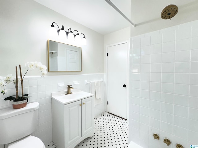 bathroom featuring tile walls, a shower, vanity, and toilet