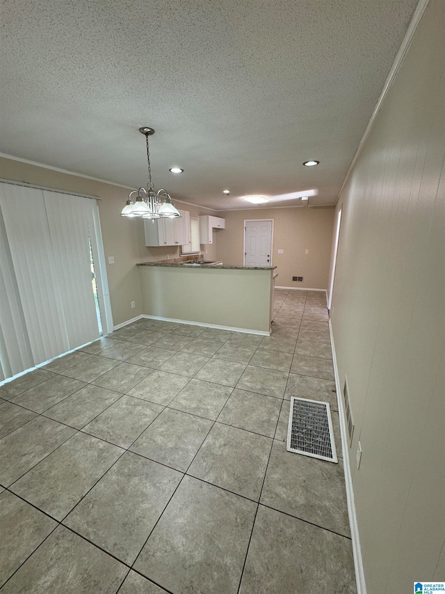 interior space featuring ornamental molding, a textured ceiling, kitchen peninsula, and white cabinetry