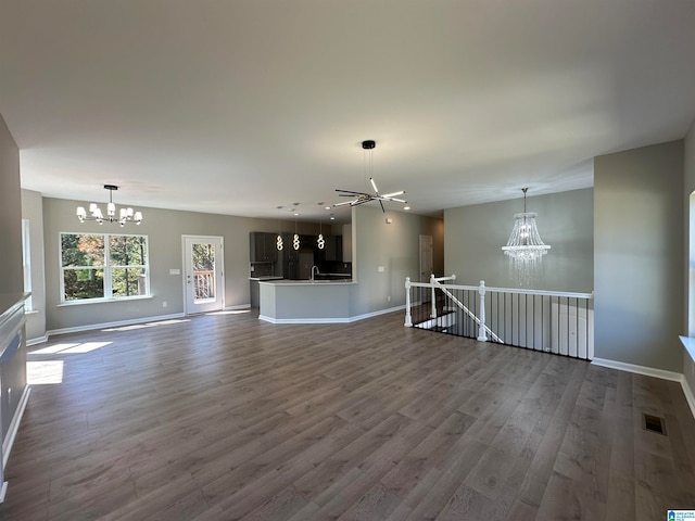 unfurnished living room with a notable chandelier, sink, and hardwood / wood-style flooring