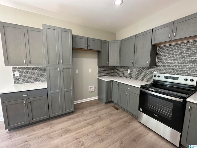 kitchen with stainless steel range with electric cooktop, light wood-type flooring, decorative backsplash, and gray cabinetry